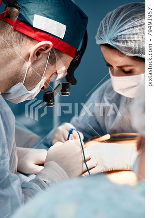 Surgeon assistant feeds coagulator, plastic surgery, professional doctors, close-up. Surgeon assistant feeds coagulator, plastic surgery, professional doctors, close-up. 79491957