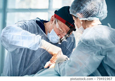 Close-up of surgeons in the operating room during the operation.Modern medicine, Medical workers during the Covid19 coronavirus pandemic fight and save lives. Close-up of surgeons in the operating room during the operation.Modern medicine, Medical workers during the Covid19 coronavirus pandemic fight and save lives. 79491967