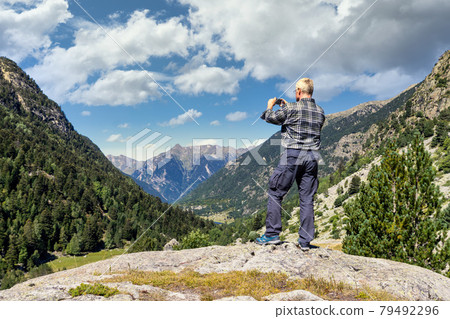 Middle aged tourist man take a picture from mountain with mobile phone 79492296