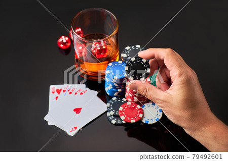 Casino chips, playing cards, glass of whiskey and dices on dark reflective background Casino chips, playing cards, glass of whiskey and dices on dark reflective background 79492601