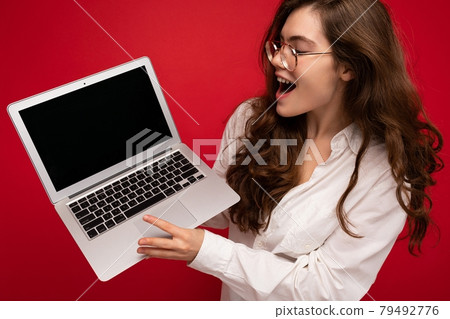 Close-up portrait of overjoyed Beautiful smiling happy young woman holding computer laptop looking 79492776