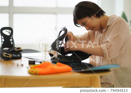 A woman grooming a snowboard board 79494815