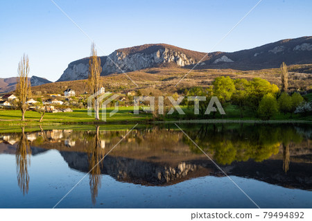A small village on the shore of a mountain lake. A dream life away from the big city. Cozy landscape A small village on the shore of a mountain lake. A dream life away from the big city. Cozy landscape 79494892