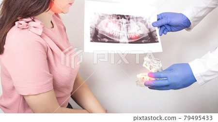 A girl at the dentist s office who has pulpitis of the tooth and damage to the tooth enamel 79495433