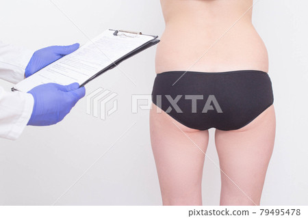 A plastic surgeon examines a patient s buttocks before installing silicone implants. The concept of buttock enlargement, shaping and volume, figure correction A plastic surgeon examines a patient s buttocks before installing silicone implants. The concept of buttock enlargement, shaping and volume, figure correction 79495478