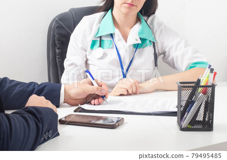 The patient signs a document for consent to anesthesia and surgery 79495485