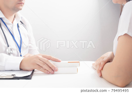 The doctor holds out medicines to the patient in the doctor's office. Concept for the sale of homeopathic medicines and biologically active food supplements. Anologist of expensive drugs, copy space 79495495