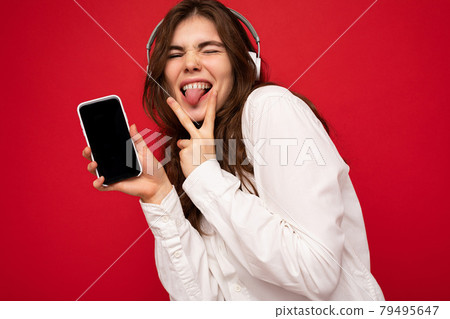 Attractive sexy positive young brunette curly woman wearing white shirt isolated on red background 79495647