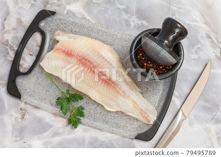 Fillet of raw pangasius fish with parsley on cutting board Fillet of raw pangasius fish with parsley on cutting board 79495789