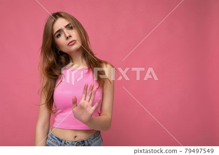 Serious upset young attractive dark blonde woman with sincere emotions isolated on background wall 79497549