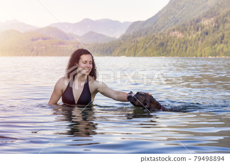 Caucasian Woman swimming in a lake with dog 79498894