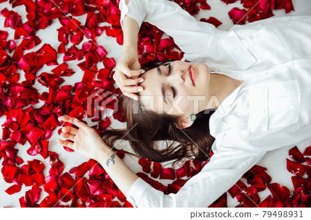 beautiful woman lies among the red petals of rose flowers beautiful woman lies among the red petals of rose flowers 79498931