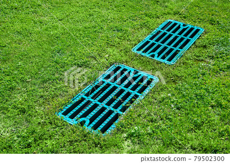 manhole drainage grates on the lawn with green grass septic tank cover, sump cesspool drainage system environment design side view with copy space, nobody. 79502300