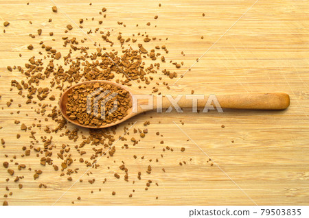 Fresh granules of instant coffee grains, in wooden spoon, on wooden background Fresh granules of instant coffee grains, in wooden spoon, on wooden background 79503835