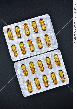 Yellow fish oil oval pills packed, isolated on black background, medical oval pills tablets Yellow fish oil oval pills packed, isolated on black background, medical oval pills tablets 79503967
