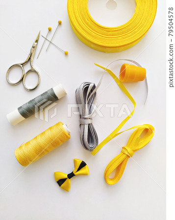 Flat lay with sewing kit and sewing accessories in trend Illuminating yellow and ultimate gray ribbon colours 79504578