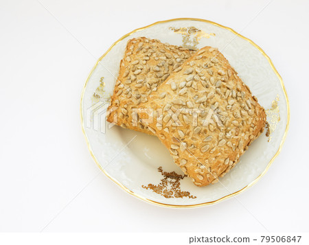 Sunflower bun on porcelain decorated plate on white background Sunflower bun on porcelain decorated plate on white background 79506847