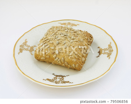 Sunflower bun on porcelain decorated plate on white background Sunflower bun on porcelain decorated plate on white background 79506856