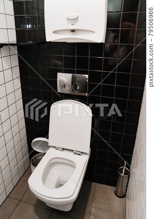 toilet in a small toilet room with black and white ceramic tiles on the walls. toilet in a small toilet room with black and white ceramic tiles on the walls. 79506966