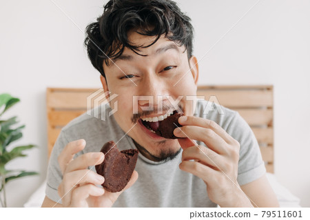Funny very delicious happy face of man eat a chocolate cookie. 79511601