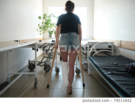 A woman with a broken leg uses orthopedic crutches. Leg injury. Loss of mobility. Rehabilitation after a fracture 79511682