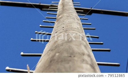 Photograph looking up a telephone pole into blue sky 79512865