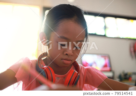 A cute Asian girl doing homework in her home during the day A cute Asian girl doing homework in her home during the day 79514541