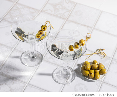 Martini cocktail with olives on the tiled table. An alcoholic classic drink with ice in an elegant glass 79521005