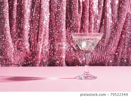 Martini cocktail background pink shiny curtain. Alcoholic classic drink with ice in elegant glass for the celebration Martini cocktail background pink shiny curtain. Alcoholic classic drink with ice in elegant glass for the celebration 79522349