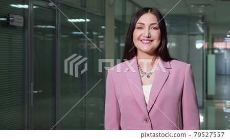 Brunette businesswoman in purple jacket poses in corridor 79527557