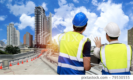 Rear view architect men standing and checking railway construction and working on skytrain with hardhat. Multiethnic business manager looking in future with building and cityscape background. 79530555