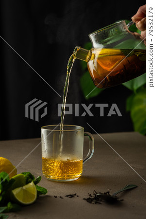 Woman pouring hot black tea 79532179