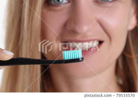 Smiling woman holding toothbrush in front of her closeup Smiling woman holding toothbrush in front of her closeup 79533570