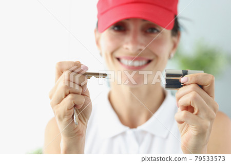 Smiling woman in red cap holding key and keyhole closeup Smiling woman in red cap holding key and keyhole closeup 79533573