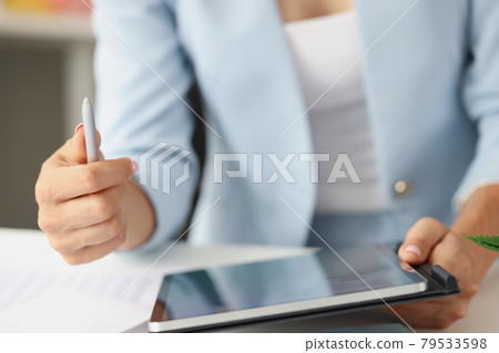 Woman in business suit holding digital tablet and stylus in her hands closeup Woman in business suit holding digital tablet and stylus in her hands closeup 79533598