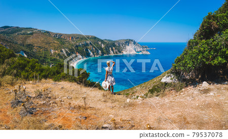 Panoramic aerial photo of a tourist woman enjoying beautiful Petani beach on Kefalonia Ionian island, Greece, during her summer vacation holiday 79537078