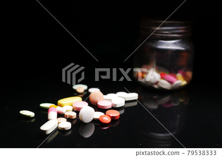 Close up of many colorful pills and capsules on black background  79538333