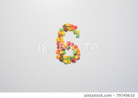 Number six from sweet pastry topping in the form of colorful foliage on a white background. Number six from sweet pastry topping in the form of colorful foliage on a white background. 79540610