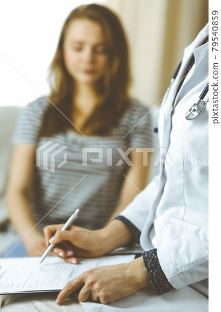 Unknown woman doctor and patient discussing current health examination while sitting in cozy living room. Stay at home concept during Coronavirus pandemic and self isolation quarantine 79540859