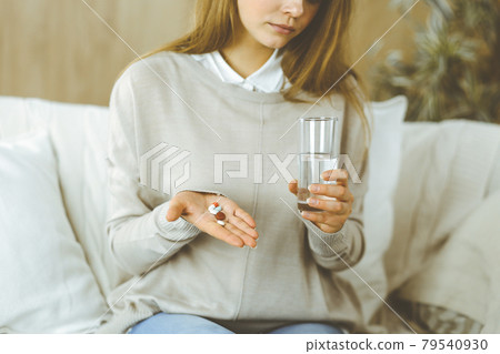 Close-up woman holding pills time to take medications, cure for headache, high blood pressure pain killer drugs at home. Stay at home concept during Coronavirus pandemic Close-up woman holding pills time to take medications, cure for headache, high blood pressure pain killer drugs at home. Stay at home concept during Coronavirus pandemic 79540930