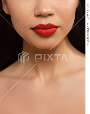 Cosmetics, makeup and trends. Bright lip gloss and lipstick on lips. Closeup of beautiful female mouth with natural lip makeup. Beautiful part of female face. Perfect clean skin in red light 79541447