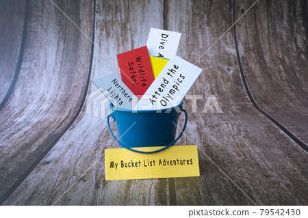 My bucket list adventures written on a colorful paper inside of a blue bucket 79542430