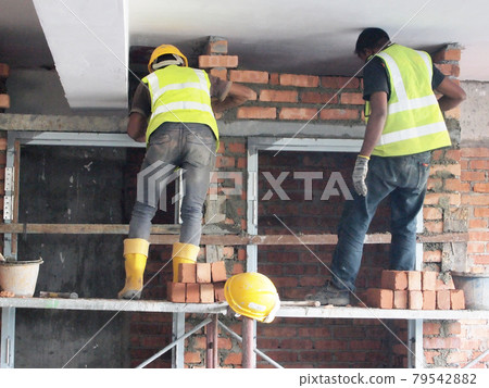 JOHOR, MALAYSIA -DECEMBER 05, 2016: Bricklayer lay bricks to form building walls at the construction site. JOHOR, MALAYSIA -DECEMBER 05, 2016: Bricklayer lay bricks to form building walls at the construction site. 79542882