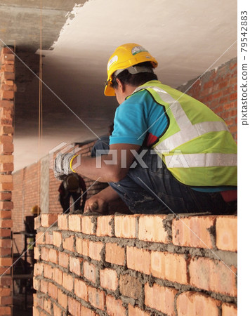 JOHOR, MALAYSIA -DECEMBER 05, 2016: Bricklayer lay bricks to form building walls at the construction site. JOHOR, MALAYSIA -DECEMBER 05, 2016: Bricklayer lay bricks to form building walls at the construction site. 79542883