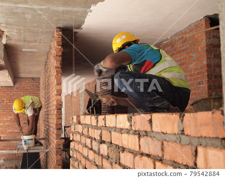 JOHOR, MALAYSIA -DECEMBER 05, 2016: Bricklayer lay bricks to form building walls at the construction site. JOHOR, MALAYSIA -DECEMBER 05, 2016: Bricklayer lay bricks to form building walls at the construction site. 79542884