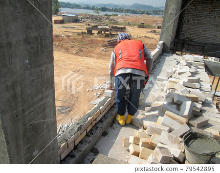 JOHOR, MALAYSIA -DECEMBER 05, 2016: Bricklayer lay bricks to form building walls at the construction site. JOHOR, MALAYSIA -DECEMBER 05, 2016: Bricklayer lay bricks to form building walls at the construction site. 79542895