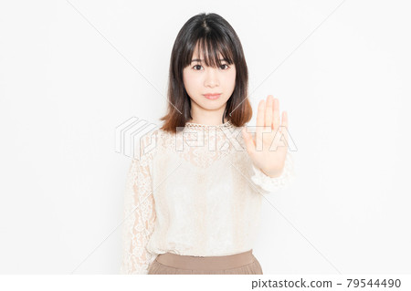 Young woman in lace blouse standing in front of white background and making NG gestures 79544490