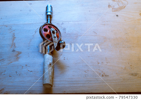 Old hand drill. An old tool. Drill lying on a dirty table. Old hand tools. Old hand drill. An old tool. Drill lying on a dirty table. Old hand tools. 79547330