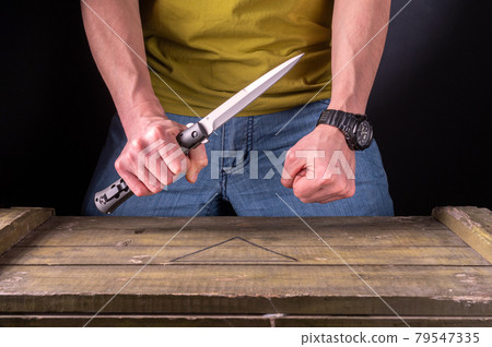 Hold a large knife in your hand. Two hands in the frame. The man attacks with a knife. Hold a large knife in your hand. Two hands in the frame. The man attacks with a knife. 79547335