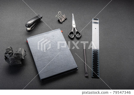 Black office supplies on a black table. Black ruler and black notebook. Front view at an angle. 79547346